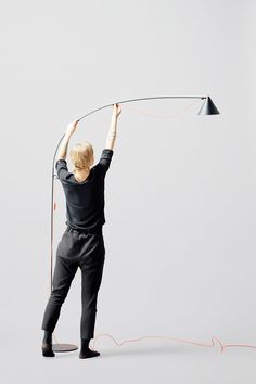 a man holding a lamp above his head while standing in front of a gray background