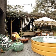 a hot tub sitting on top of a wooden deck next to two lawn chairs and an umbrella