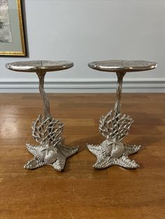 two silver candlesticks sitting on top of a wooden floor