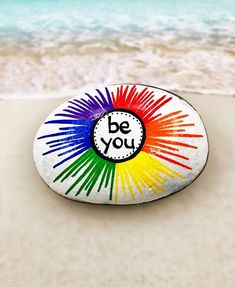 a rock with the words be you painted on it sitting in the sand at the beach