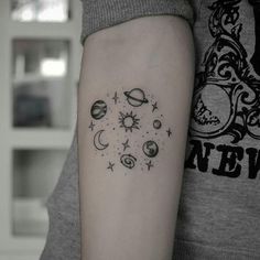 a woman's arm with a tattoo on it that has planets and stars in the middle