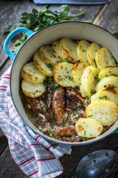 a pot filled with potatoes and meat on top of a wooden table