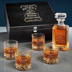 four whiskey glasses in front of a wooden box with an engraved label on the side