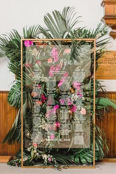 a wedding seating chart with pink flowers and greenery