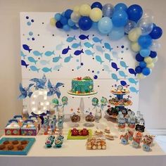 a birthday party with blue and white balloons, cake, cupcakes and decorations