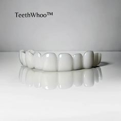 a tooth model sitting on top of a white table next to a wall with the words teeth whoom written above it