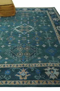 a green rug with blue, yellow and white designs on the floor next to a chair