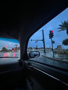 the view from inside a car looking at traffic lights and palm trees in the distance