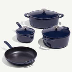 three blue pots and two pans on a white surface