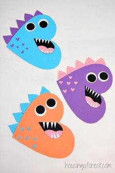 three paper monsters with mouths and hearts on their faces, one is purple and the other is orange