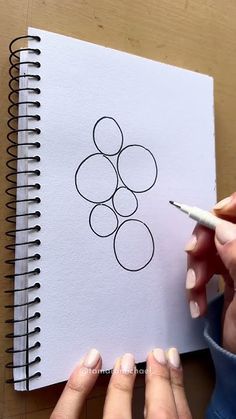 a woman is holding a pencil and drawing on a piece of paper with circles in it