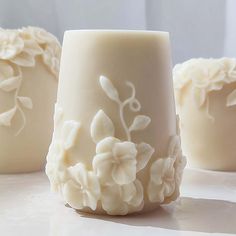 three white vases sitting on top of a table next to each other with flowers painted on them