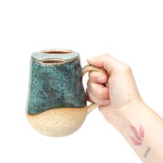 a person holding a ceramic mug in their hand