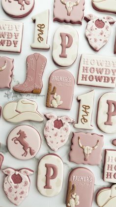 pink and white decorated cookies with horse, boots, hearts, and letters on them