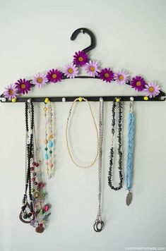 a rack with several necklaces hanging from it's sides and flowers on the top