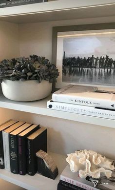 books and pictures are sitting on shelves in a room that is decorated with white bookcases