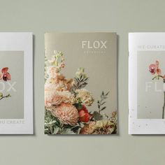 three books with flowers on them sitting next to each other in front of a gray wall