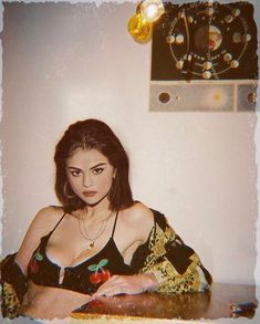 a woman sitting on top of a wooden table next to a wall with a clock