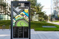 a bus stop sign with a map on it in the middle of a city park