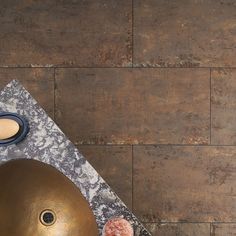 an overhead view of a large metal object on a marble table with two doughnuts next to it