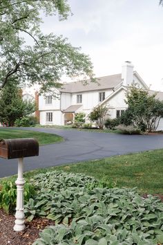 a mailbox sitting in the middle of a lush green yard next to a white house