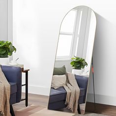 a large mirror sitting on top of a wooden floor next to a chair and potted plant