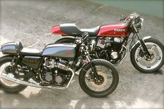 two motorcycles parked next to each other in a parking lot with concrete flooring behind them