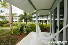 a white hammock hanging from the side of a building next to palm trees