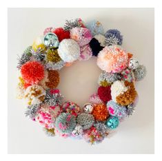 a multicolored knitted christmas wreath hanging on a wall