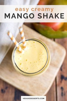 an easy creamy mango shake in a glass with two straws on the side