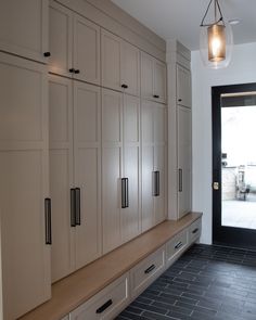 a kitchen with white cabinets and black tile flooring next to an open glass door