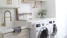 a washer and dryer in a white laundry room with gold handles on the door