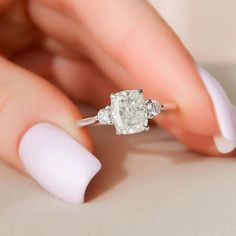 a woman's hand holding an engagement ring