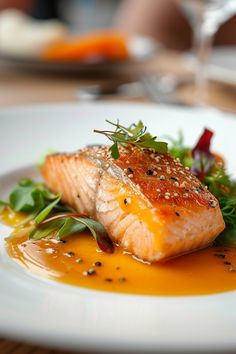 a white plate topped with fish covered in sauce and garnished with green leaves