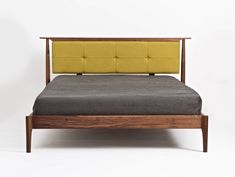 a bed with a wooden frame and yellow headboard on top of it, against a white background