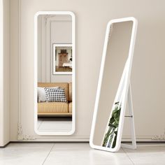 a white mirror sitting on top of a floor next to a couch in a living room