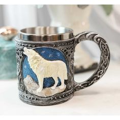 a silver mug with a white wolf on the front and blue ground in the back