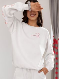 Indulge in the charm of our Adorable White Coquette Sweatshirt - the epitome of soft girl style with delightful coquette bows adorning both sleeves and a sweet heart-shaped ribbon on the left upper chest. This oversized sweatshirt, available in standard and plus sizes, offers the perfect blend of comfort and style. The gorgeous pink coquette ribbons add a touch of sweetness to this warm white sweatshirt, making it an ideal gift for her or anyone who appreciates the soft girl aesthetic or coquette style. Crafted from a medium-heavy fabric blend of 50% cotton and 50% polyester, this sweatshirt ensures a cozy feel, making it the perfect choice for colder months. The classic fit, crew neckline, and double-needle stitching provide both comfort and durability. Say goodbye to itchy side seams wit Trendy Heart Graphic Tops For Loungewear, Trendy Loungewear Tops With Heart Graphic, Trendy Heart Print Tops For Loungewear, Heart Graphic Relaxed Fit Top For Loungewear, Heart Print Crew Neck Top For Loungewear, Relaxed Fit Heart Graphic Top For Loungewear, Relaxed Fit Loungewear Tops With Heart Graphic, Oversized Long Sleeve Top With Heart Graphic, White Heart Print Tops For Loungewear