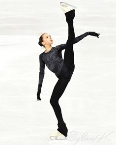 a female figure skating on the ice with her arms in the air and one leg up