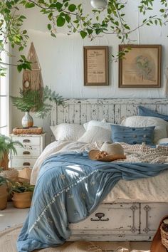 a white bed with blue sheets and pillows in a bedroom next to potted plants