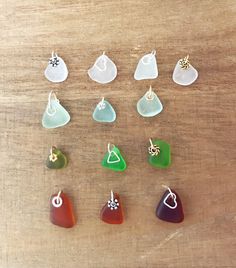 seven different colored glass earrings sitting on top of a wooden table