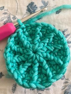 a crochet potholder with a pink handle on a floral print tablecloth