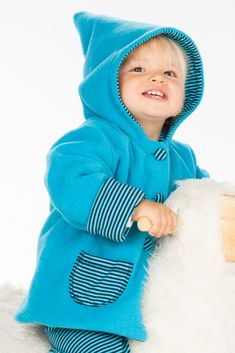 a little boy that is sitting on top of a teddy bear wearing a blue outfit