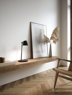 an empty room with a chair, lamp and pictures on the shelf in front of it