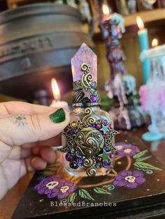 a person holding a small candle in front of a table with some candles on it