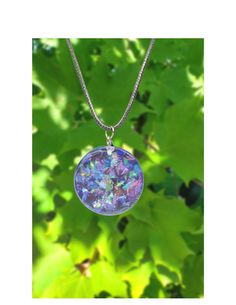 a necklace that is sitting on top of a tree branch with leaves in the background