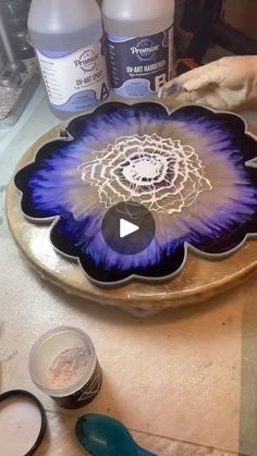 a plate with blue flowers on it sitting on a table next to paint and brushes