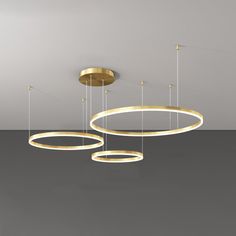 three circular lights suspended from the ceiling in an empty room with grey walls and flooring