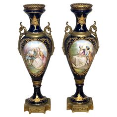 two vases with paintings on them sitting next to each other