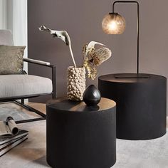 two black tables sitting next to each other on top of a carpeted floor in front of a gray wall